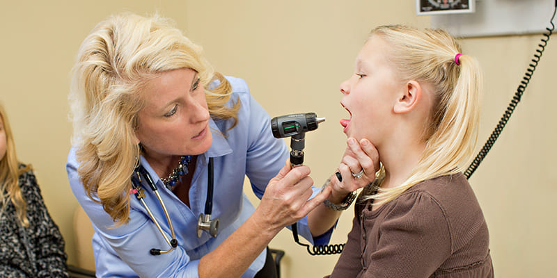 doctor checking young girl's throat